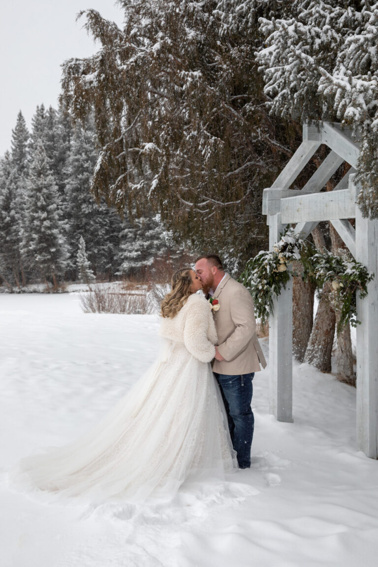 A bride and groom kiss outside in the snow after their first look on their winter elopement day.