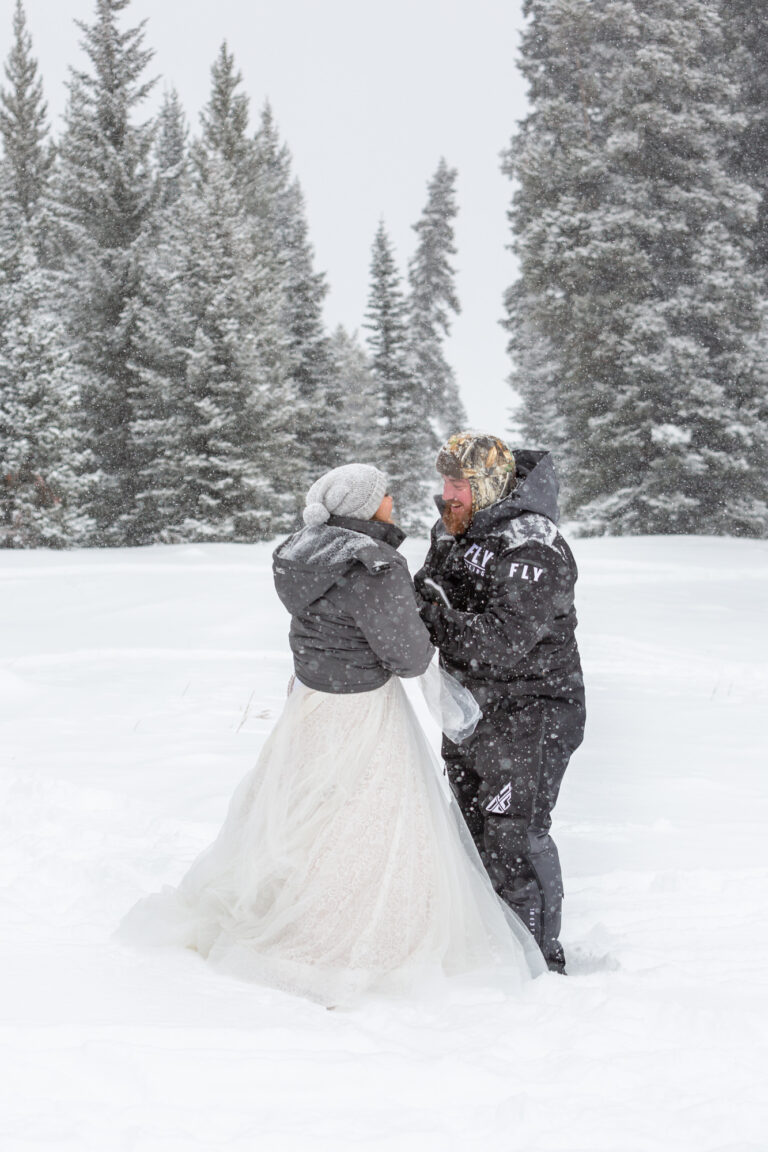 a bride and groom hold hands, laughing in the snow on their winter elopement day.