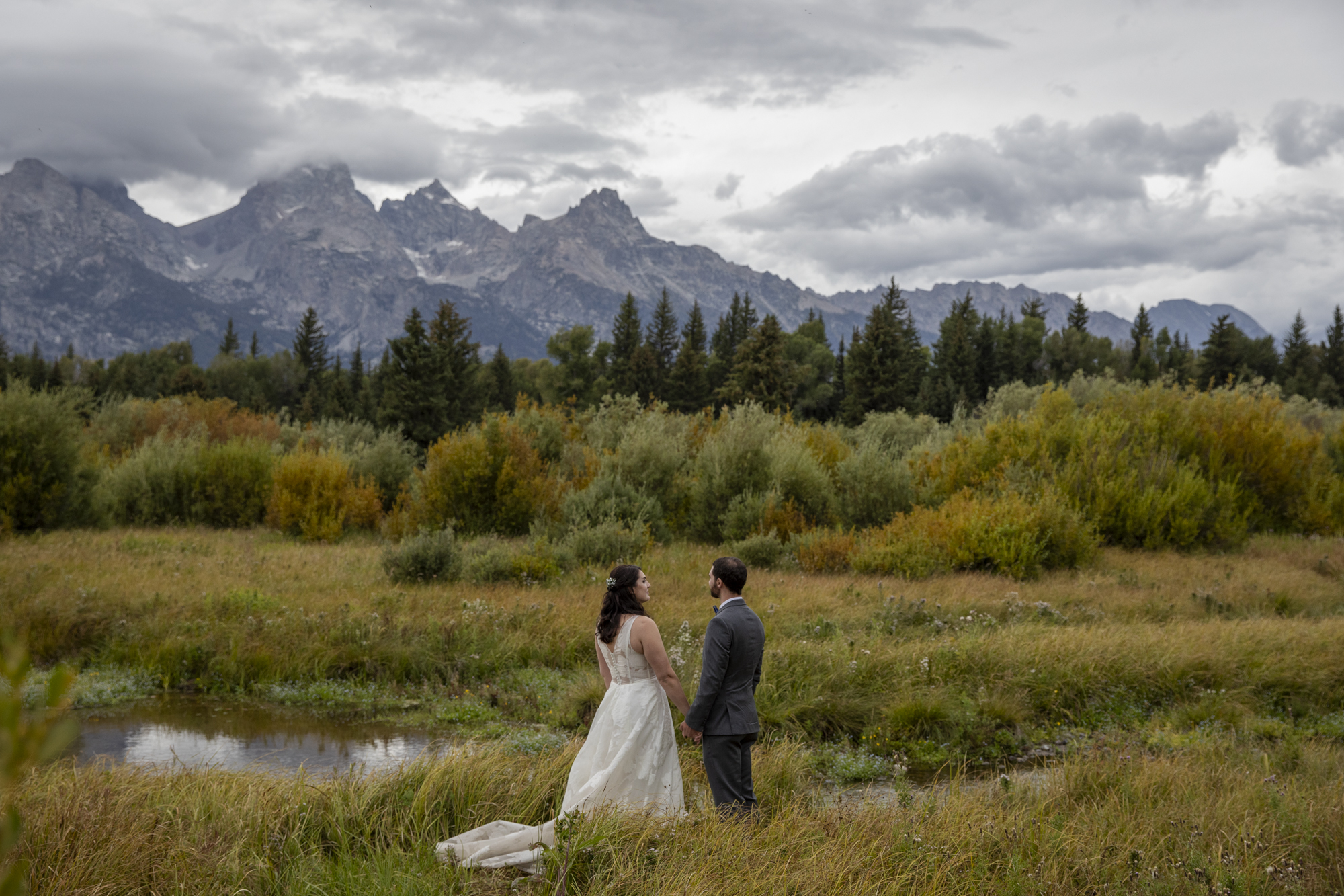 8 Incredible Places to Elope in Wyoming | Scenic Vows Bride and groom in a mountain meadow with the Tetons behind them at a scenic Wyoming elopement location
