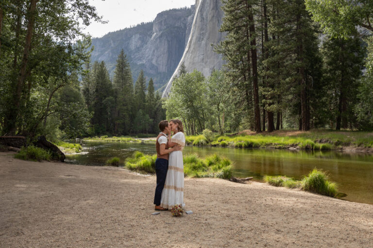 Two brides kiss on the sandy beach of Catherdral Beach in Yosemite on their elopement day.