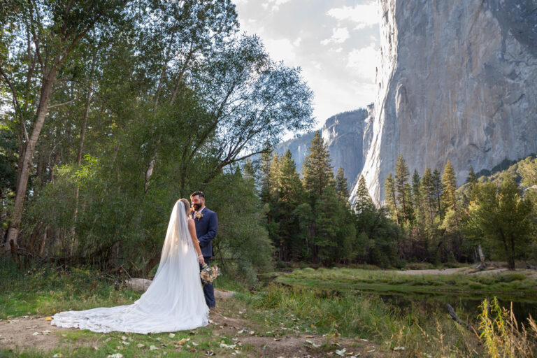 A bride stands facing her groom and holding her flowers on their Yosemite elopement day.
