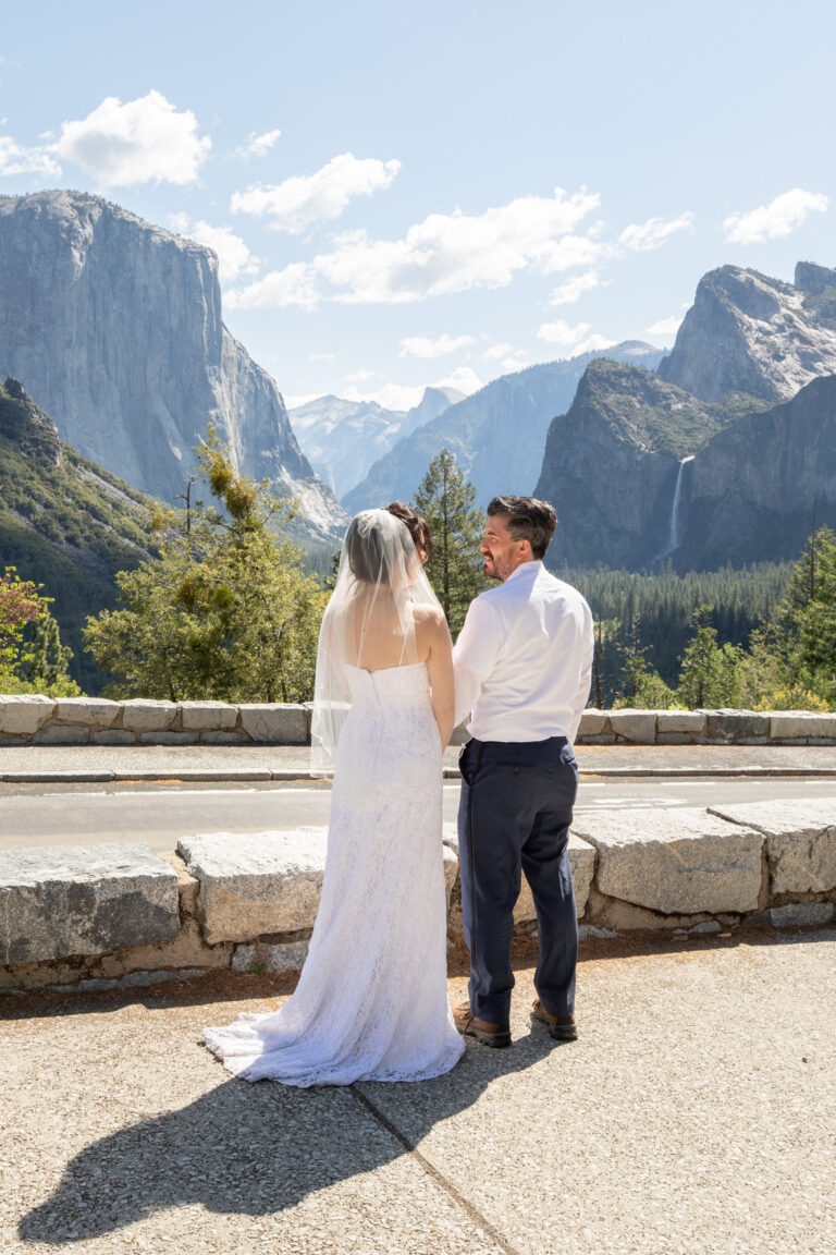 A bride and groom look at each other as they stand in front of Tunnel View on their Yosemite elopement day.
