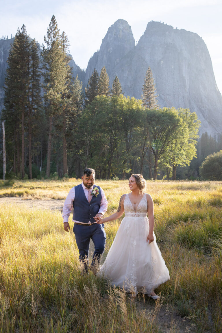 A bride and groom walk through a meadow in Yosemite after filling out their Yosemite wedding permits.